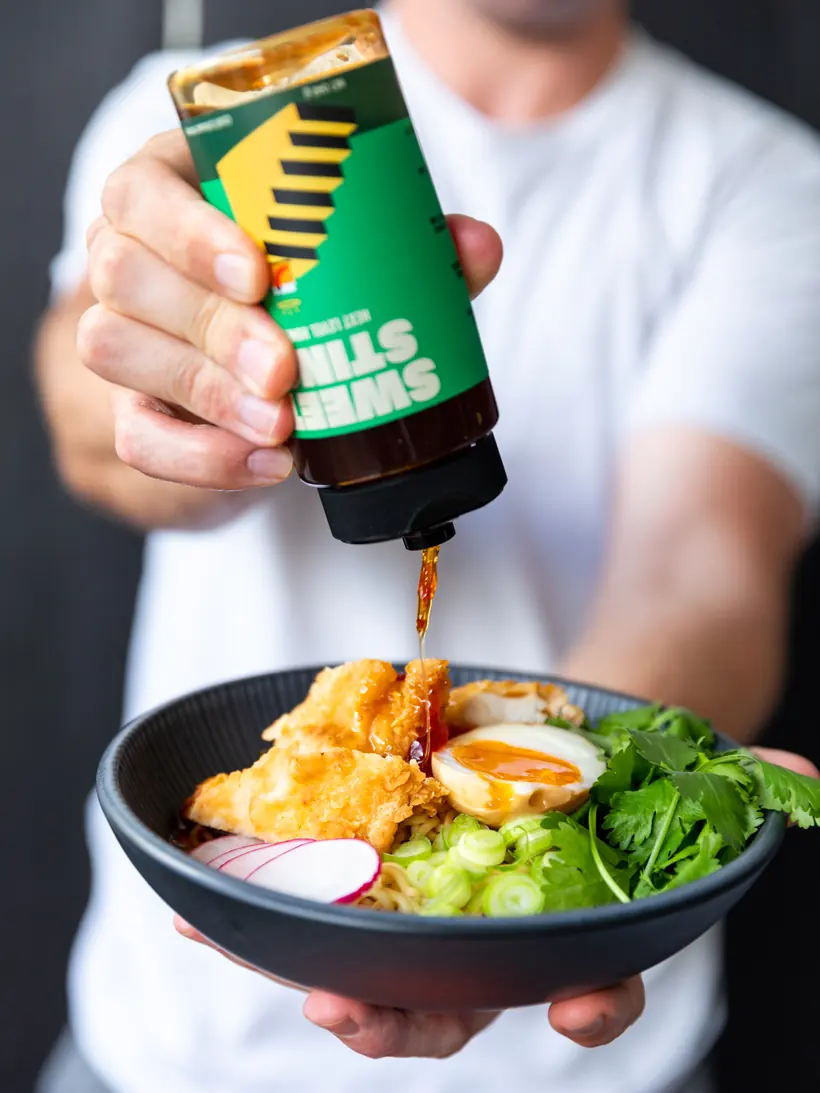 Sweet Sting hot honey being drizzled over a bowl of ramen